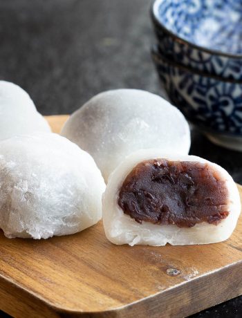 Mochi on a board with an open one showing red bean paste.