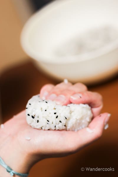 Squeezing the onigiri into a ball shape.