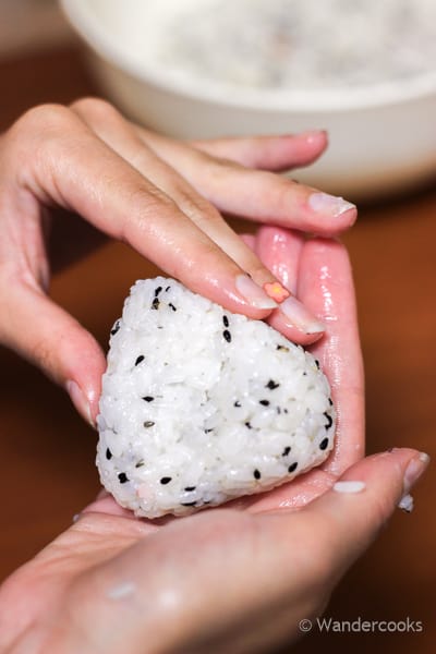 Pressing the edges of the onigiri into a triangle shape.