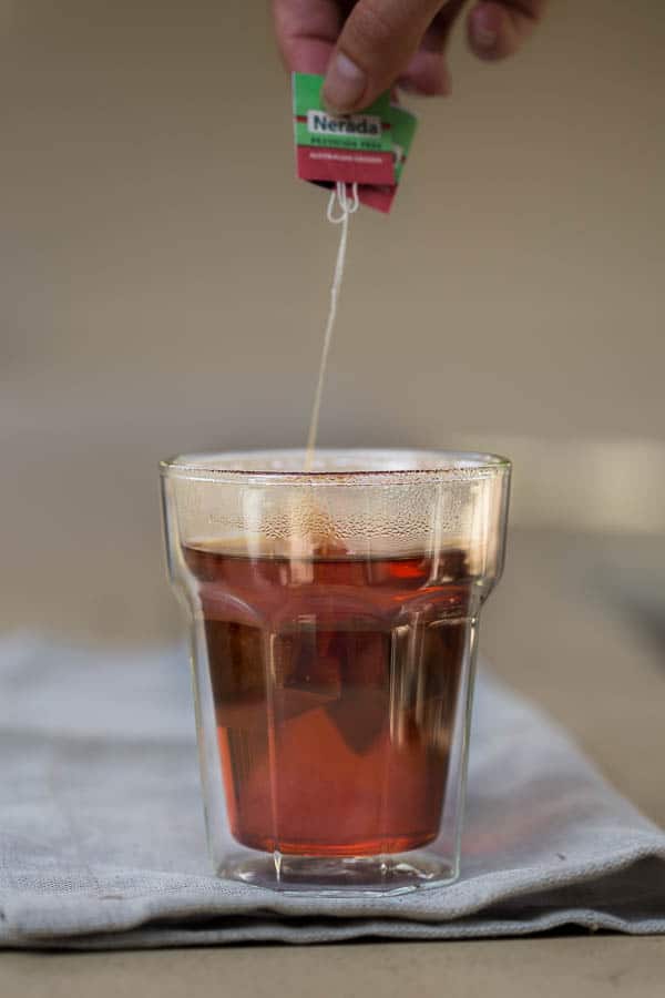 Dunking black tea bags into a clear glass.