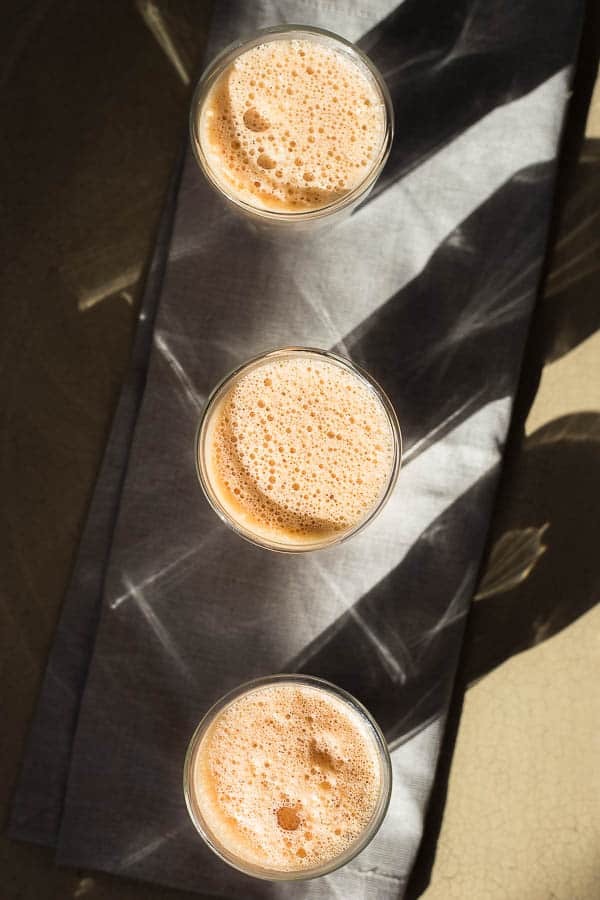 Three glasses of teh tarik lined up on a table.