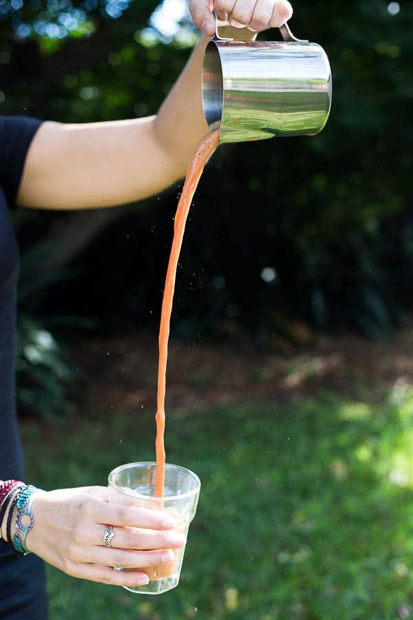 Pouring hot teh tarik between a jug and a glass.