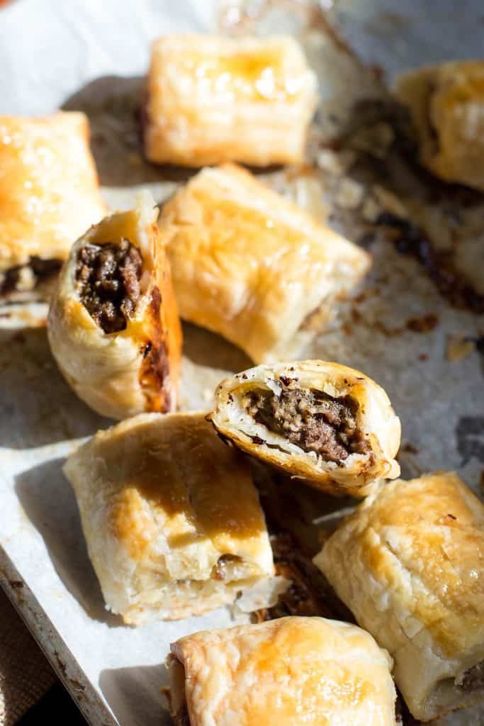 Crispy beef sausage rolls on a baking tray.