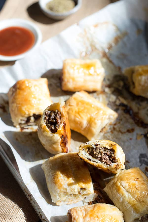 A tray of sausage rolls with tomato sauce for dipping.