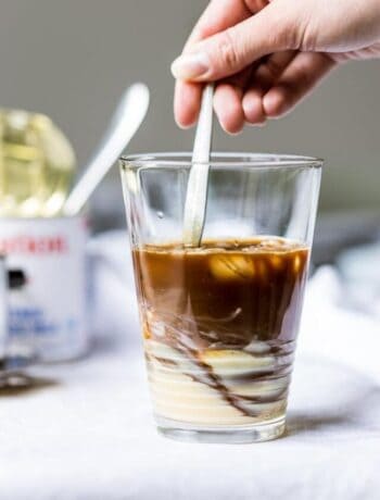 Swirling Vietnamese coffee and condensed milk in a glass.