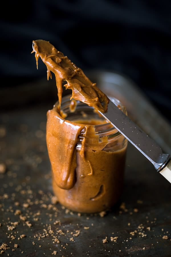 Spreading knife covered in speculoos spread, resting against a glass jar.