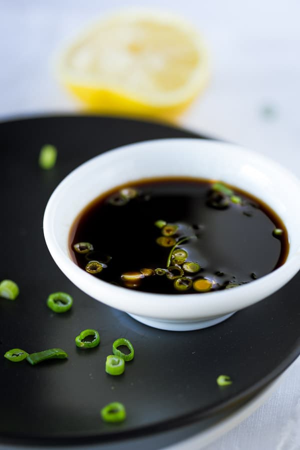 Ponzu sauce in a dipping bowl garnished with spring onion.