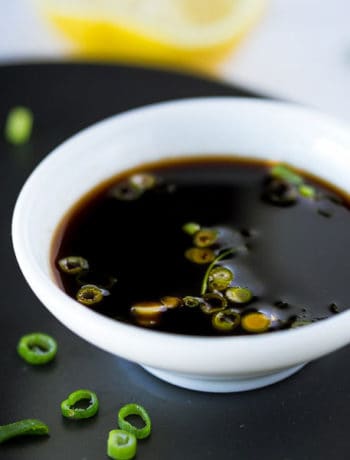 Ponzu sauce in a dipping bowl garnished with spring onion.