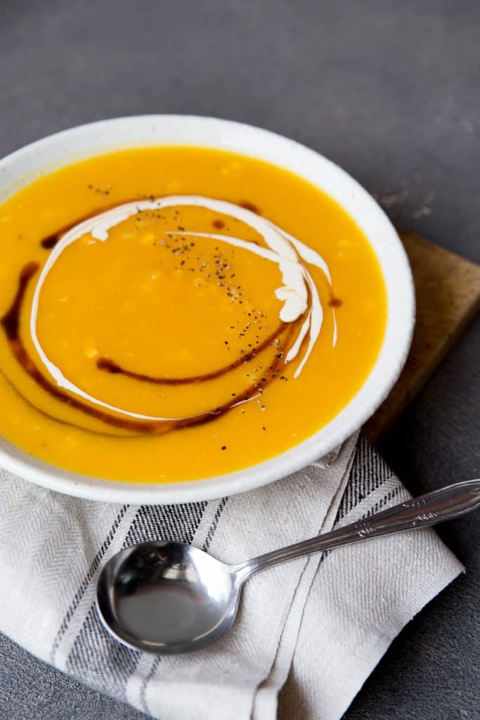Bowl of pumpkin soup with swirls of cream and Worcestershire sauce.