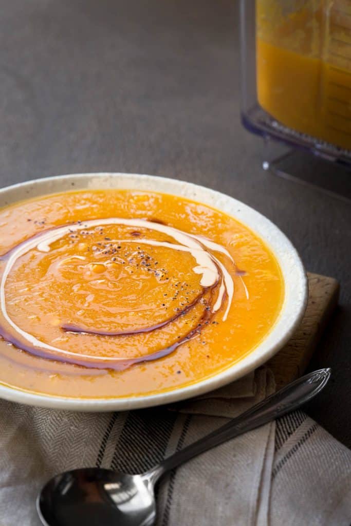 Close up of swirls of sauce and cream in pumpkin and corn soup.