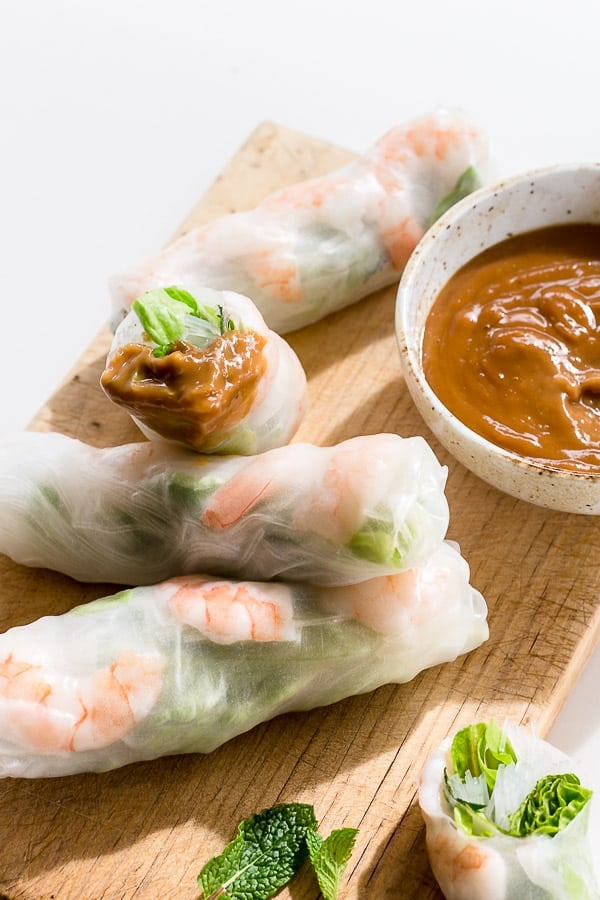 Close up of a vietnamese rice paper roll freshly dipped in sauce.