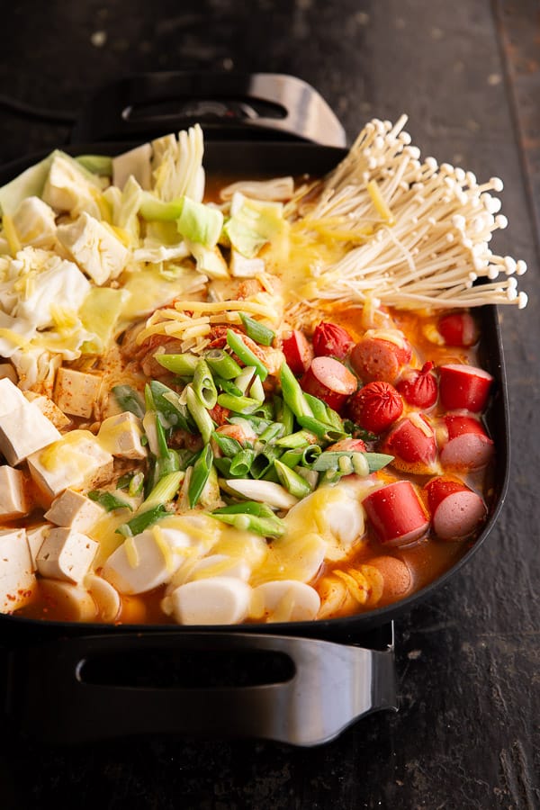 Large hot pot full of ingredients for Korean Army Stew and smothered in cheese.