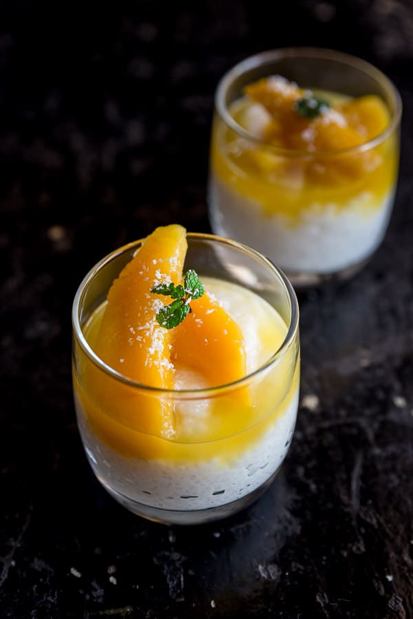 Two glasses of sago pudding topped with mango slices.
