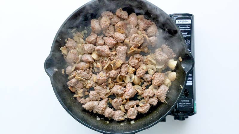 Cooking Italian sausage and mushroom in cast iron pan.