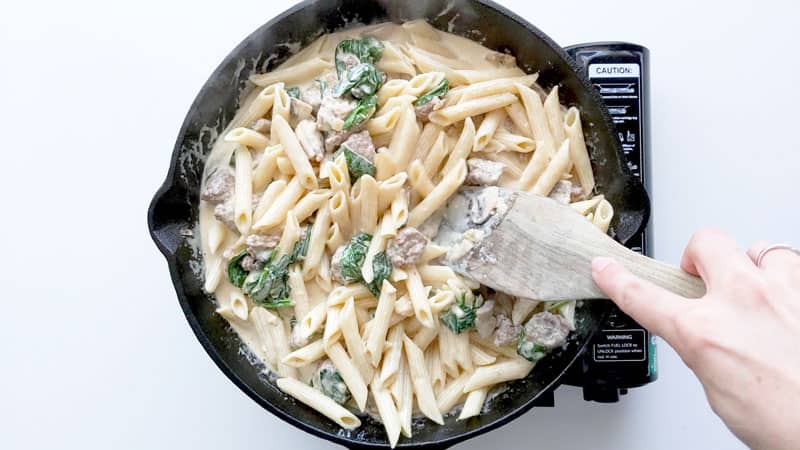 Mixing pasta in cast iron pan.