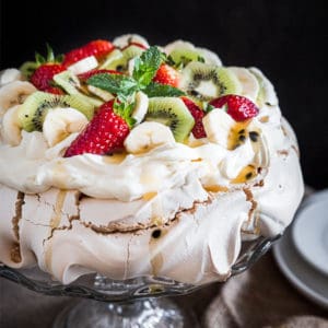 Australian Pavlova Dessert Meringue on cake stand with side plates.