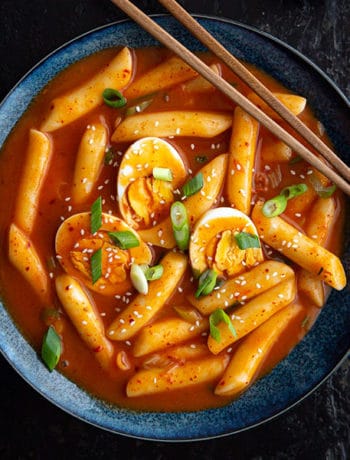 Bowl of Tteokbokki with boiled eggs and chopsticks.