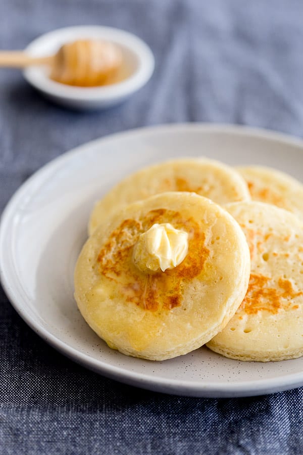 Plate of fresh crumpets with butter and honey.