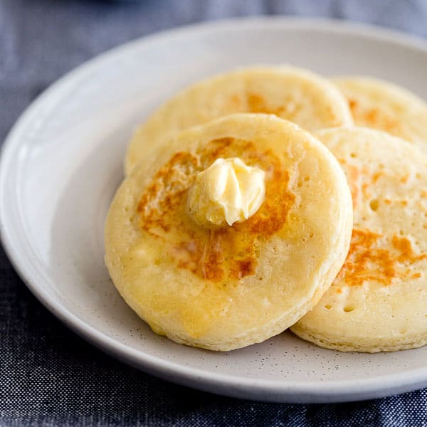 Plate of fresh crumpets with butter and honey.