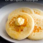Golden crumpets with butter and honey on a plate.