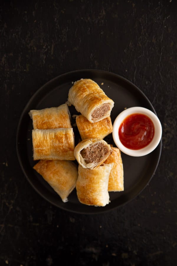 Plate of sausage rolls with tomato dipping sauce.