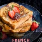 Stack of four slices of French brioche toast topped with fresh strawberries and jam.