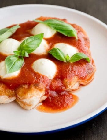 Pizza fritta on a plate topped with sauce, mozzarella and basil.