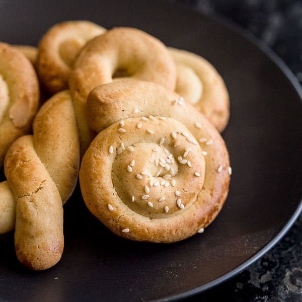 Koulourakia cookies on a plate including spiral and twist shapes.