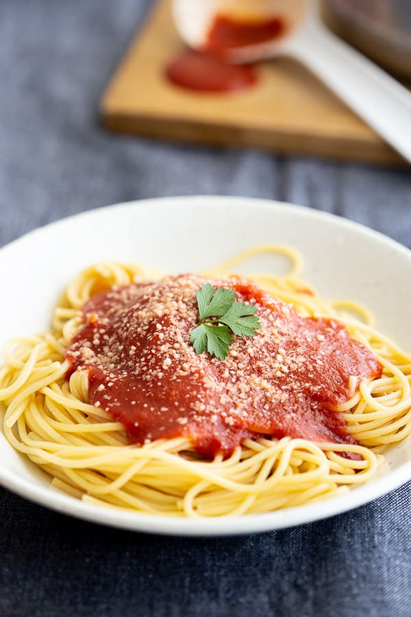 Napoli sauce topped spaghetti in white bowl.