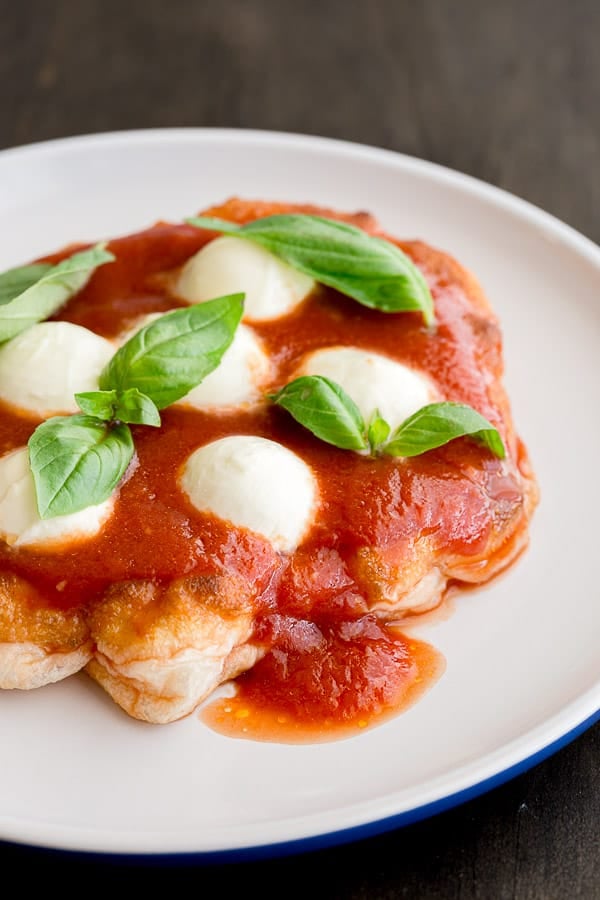 Close up of fried pizza topped with passata, bocconcini and basil.