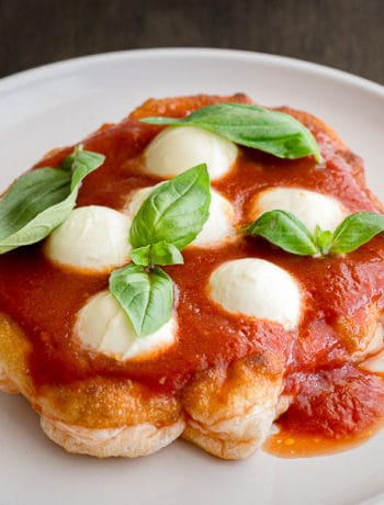 Close up of fried pizza with mozzarella and basil.
