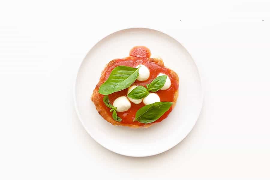 Topping pizza fritta with basil and bocconcini.