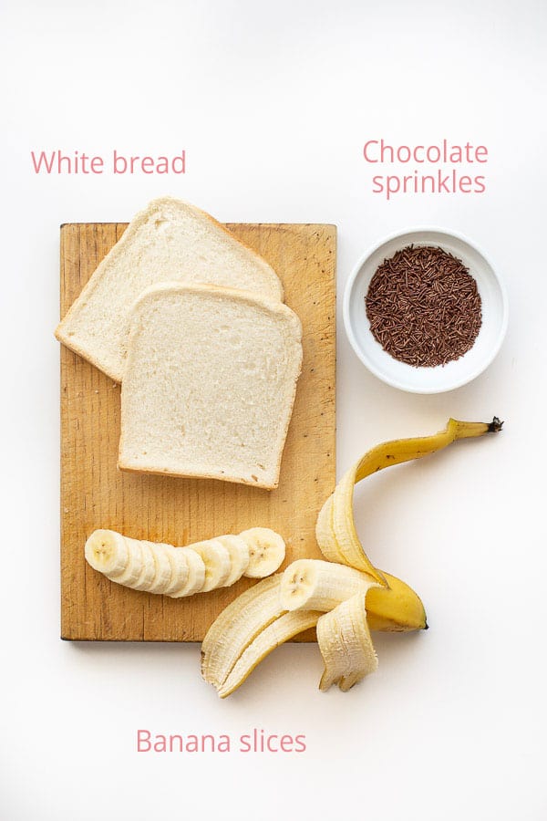 Flat lay of hagelslag ingredients including white bread, banana and chocolate sprinkles.
