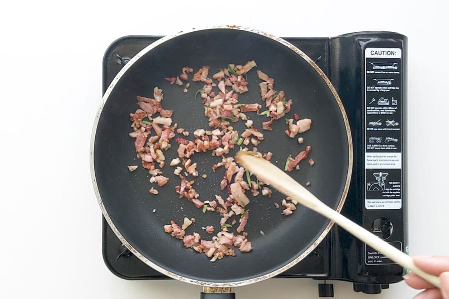 Bacon and rosemary frying in a pan.