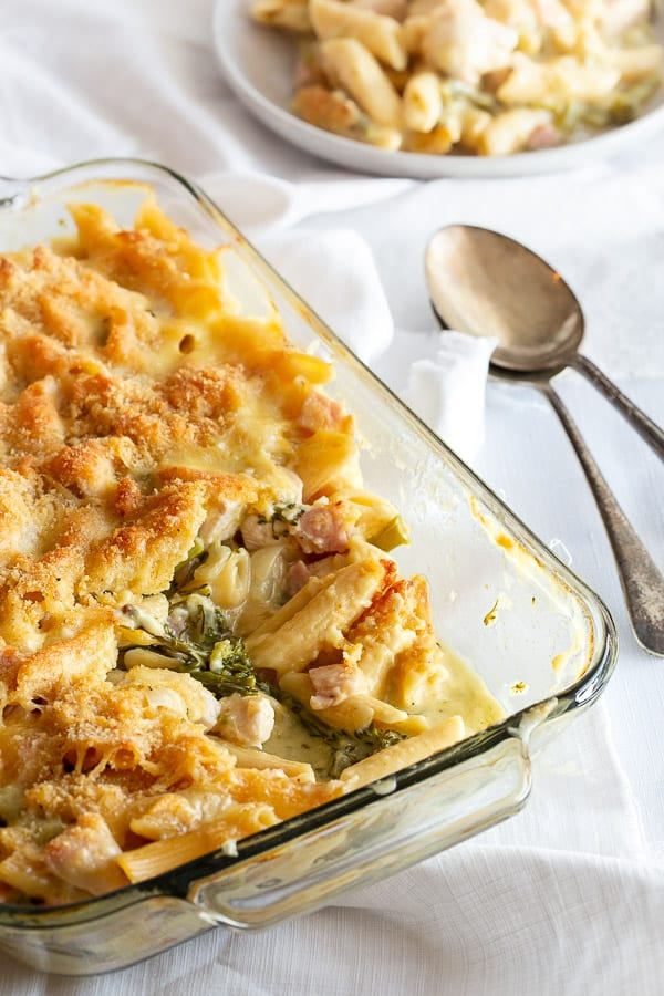 Close up of creamy chicken pasta bake with serving spoons.