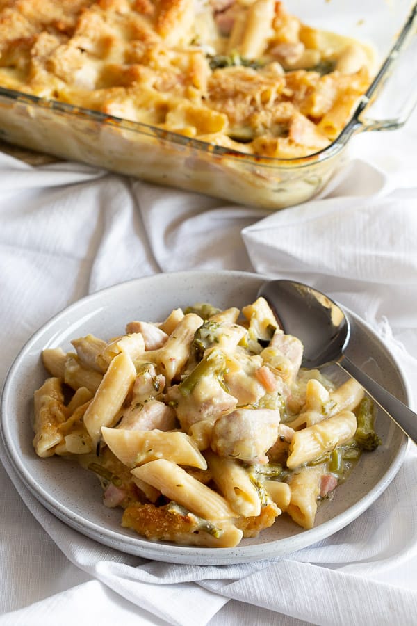 One serve of creamy chicken pasta bake on a grey plate.