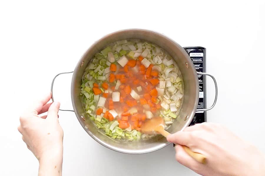 Adding the chopped vegetables into the split pea soup.