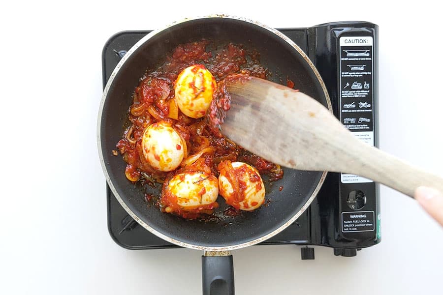 Sambal eggs being cooked in a frypan.