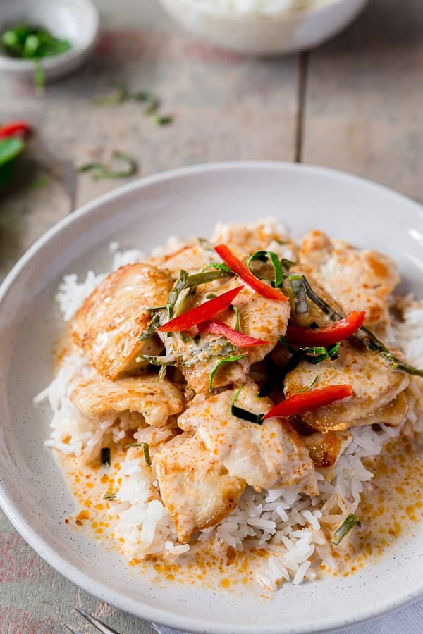 Plate of choo chee curry with chicken pieces, topped with capsicum and kaffir lime.