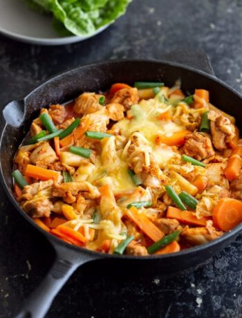 Korean spicy chicken stir fry in cast iron pot, topped with melted cheese.