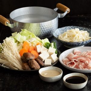 Pork, udon and vegetables all cut up and ready to eat in a shabu shabu hot pot.
