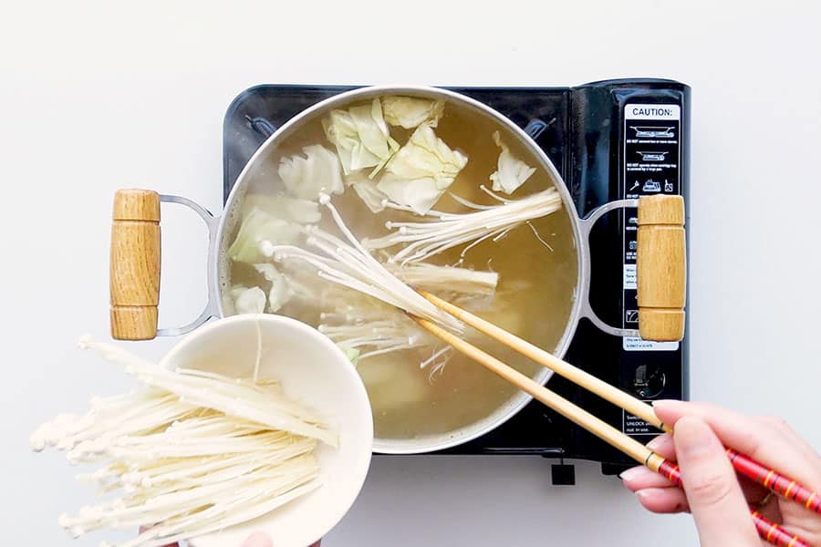 Putting enoki mushrooms into the Japanese hot pot.