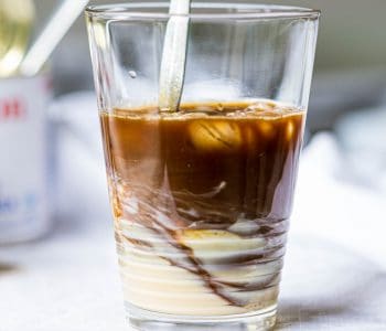 Swirling Vietnamese coffee with condensed milk in a glass.