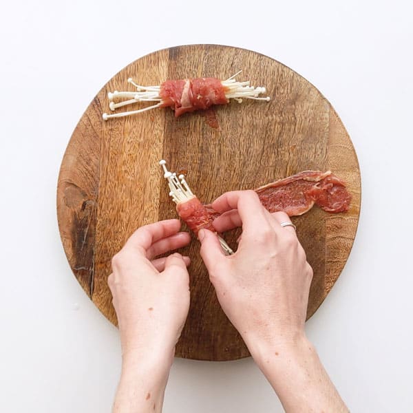Wrapping thinly sliced beef around enoki.