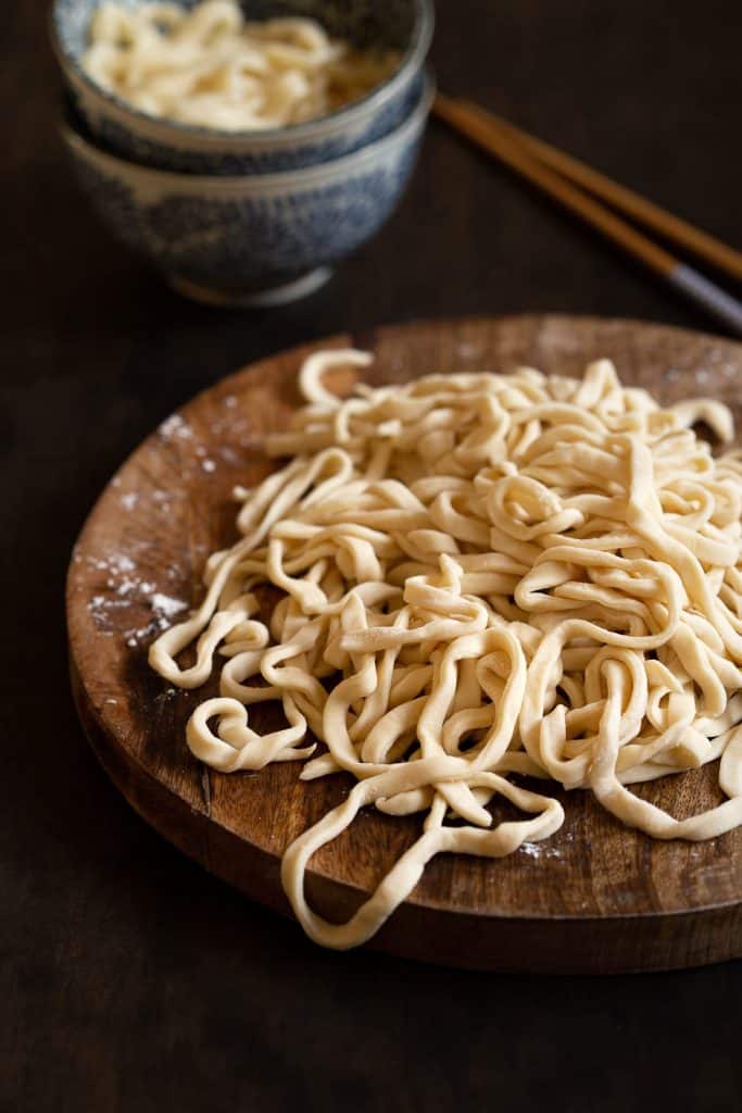 Wooden board with a pile of fresh udon noodles.