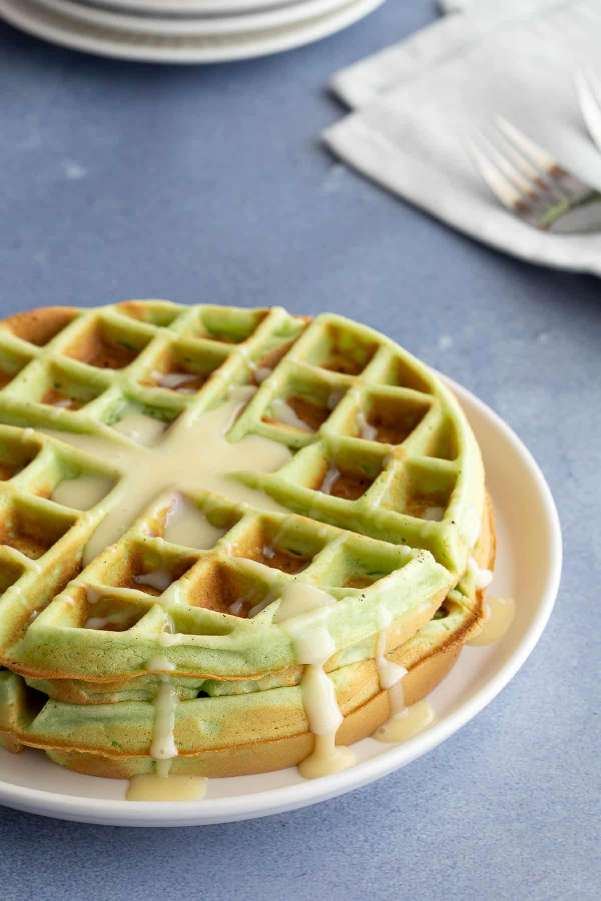 Stack of green waffles drizzled with sweetened condensed milk.