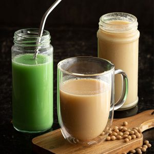 Three glasses of soy milk, with soy beans.