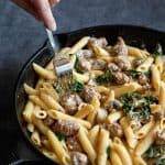 Creamy sausage pasta in a cast iron skillet.
