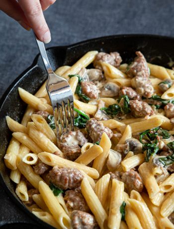 Creamy sausage pasta in a cast iron skillet.