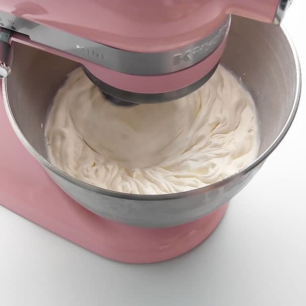 Whipping cream with sugar and vanilla to top the pavlova.
